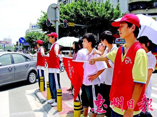 日前，惠城区桥东街道志愿者冒着烈日在市区东湖西路和康宁路交会十字路口引导市民文明出行。.jpg