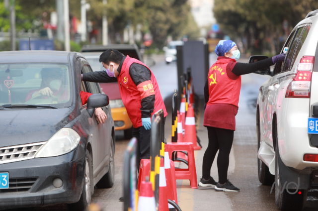 坪山区龙兴南路，党员志愿者正在对过往车辆人员检测体温。